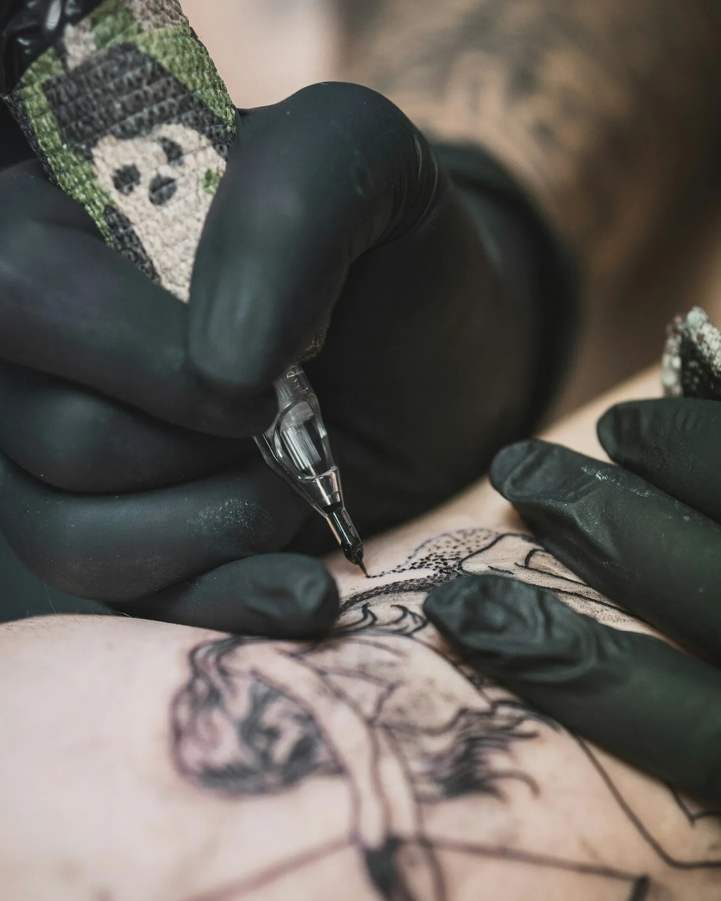 A tattoo artist working on a client