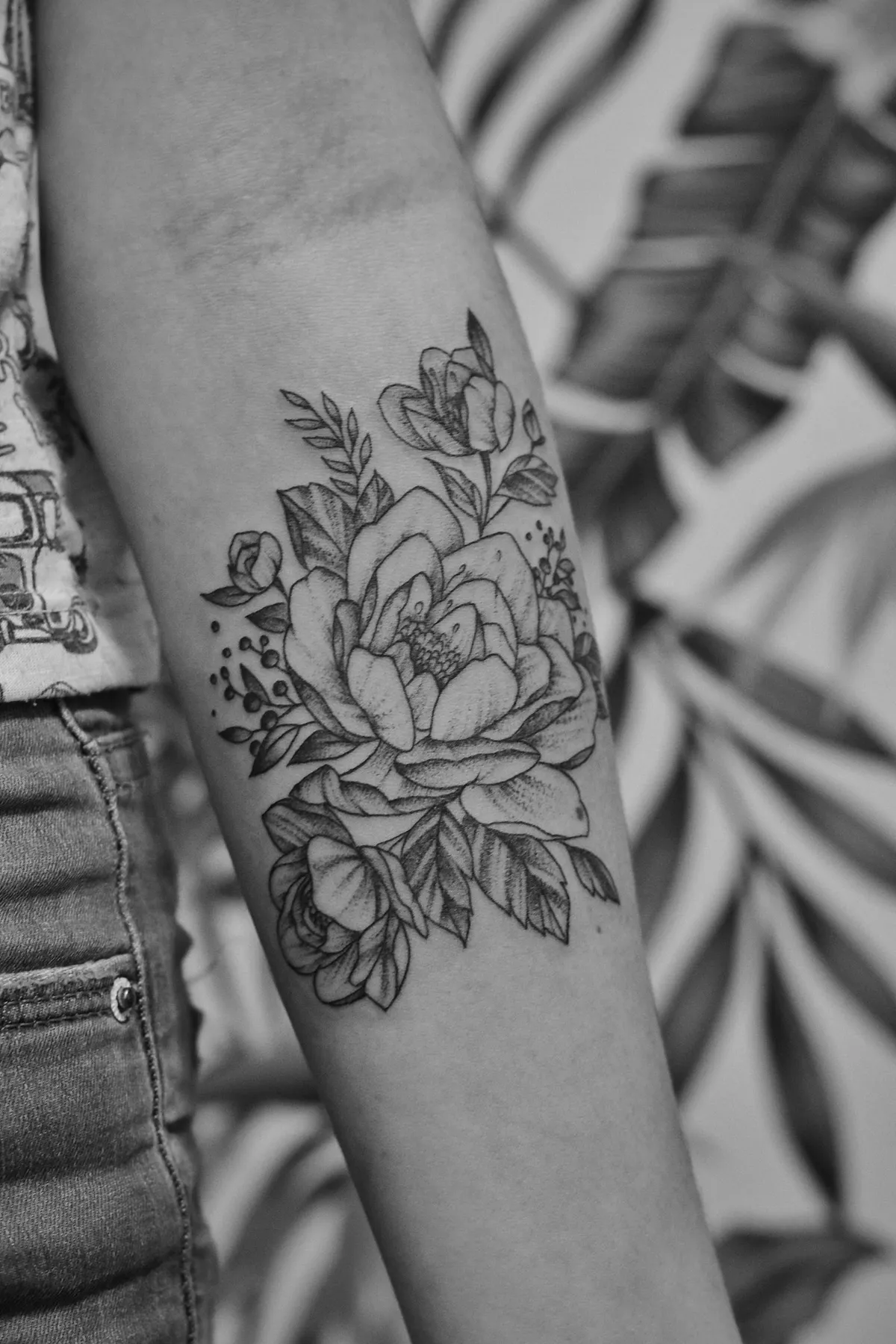 A fine-line floral piece healed on a forearm