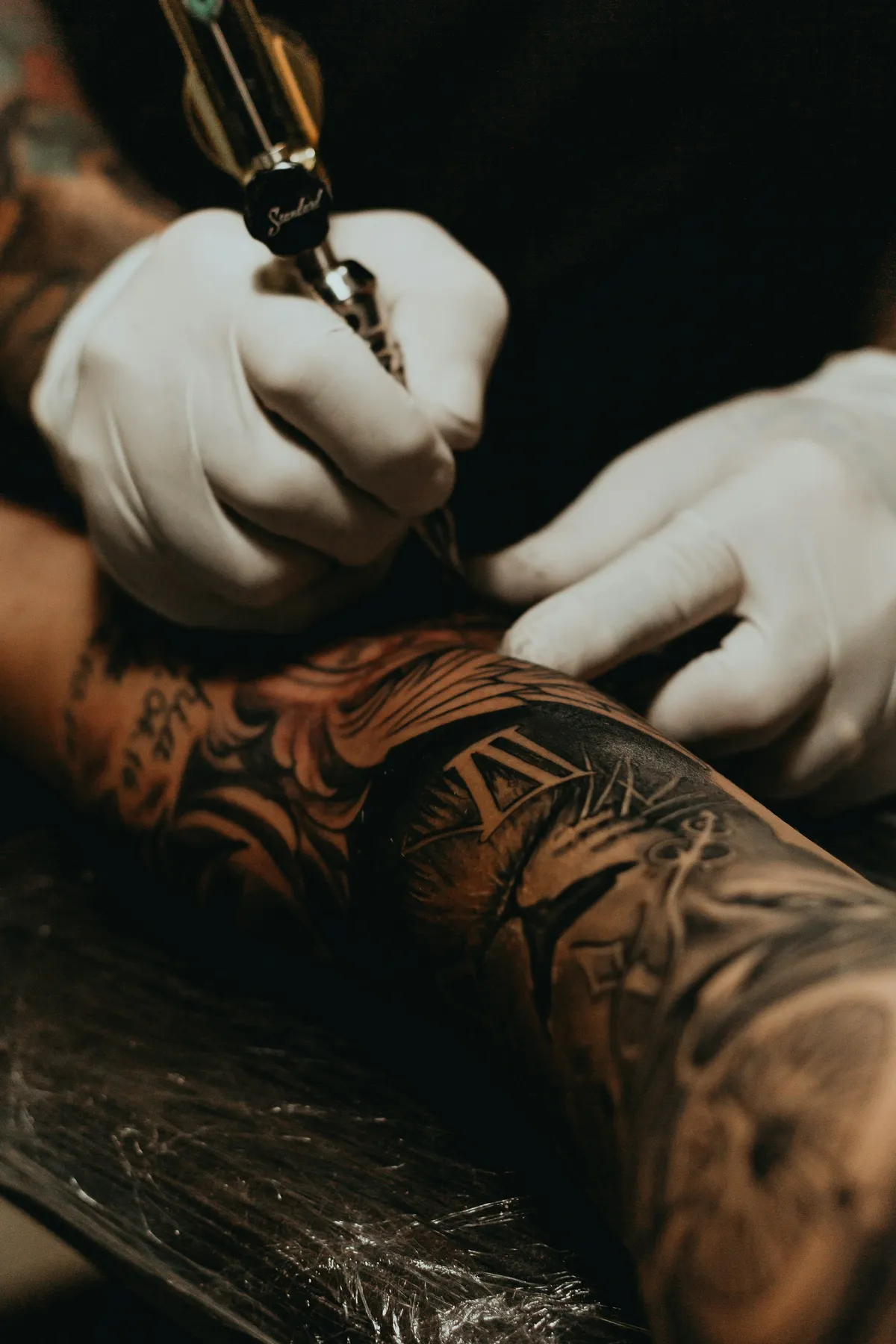 A tattoo artist at work, machine to skin